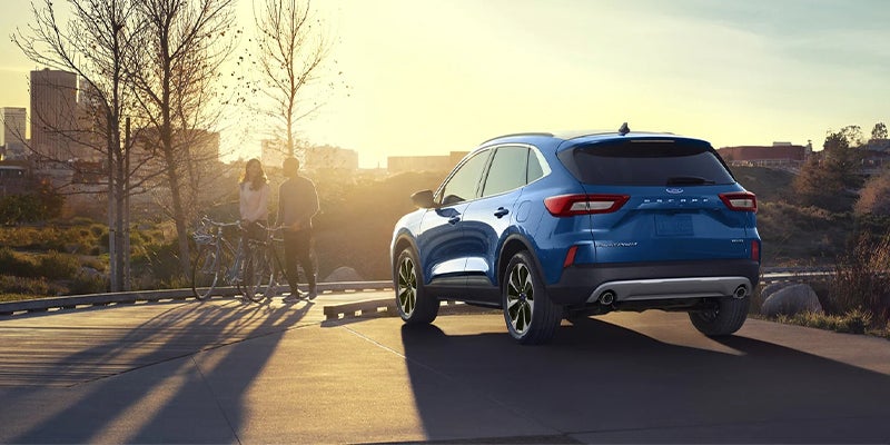 Rear view of blue 2023 Ford Escape driving on a scenic road