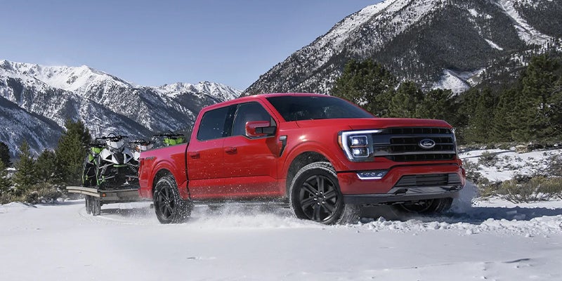 Red Ford F-150 parked in a snowy mountain setting