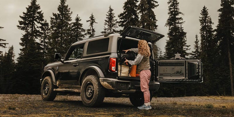 Person standing near an off-road parked Bronco in nature