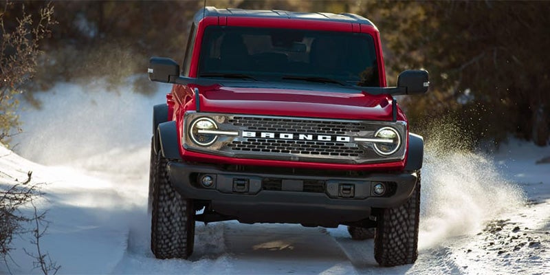 Front view of red Bronco driving through snow